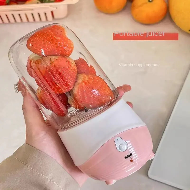 Portable juicer filled with strawberries held by a hand on a light background